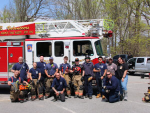 Group photo of firefighters posing infront of a white and red fire truck.