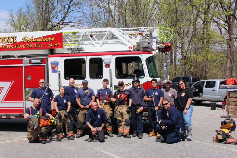 Group photo of firefighters posing infront of a white and red fire truck.